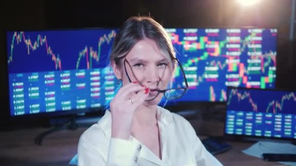 Lady broker está sentada al lado de los monitores con datos de stock — Vídeo de stock