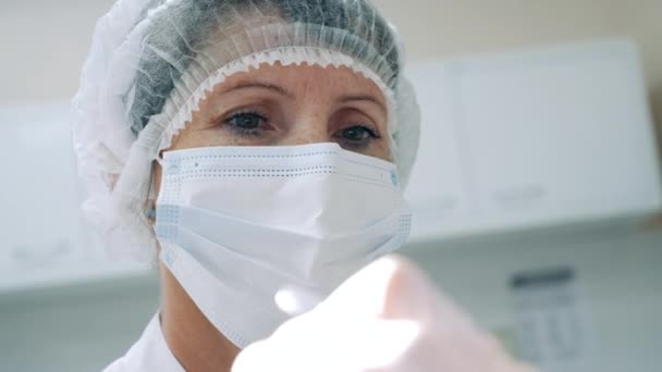 Dentista feminino em uma máscara facial e um gorro médico — Vídeo de Stock