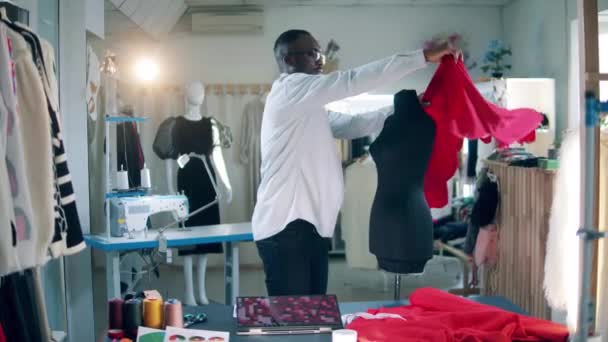 Male designer is putting a piece of red fabric onto the dummy — Stock Video