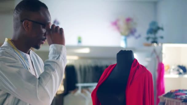 Diseñador africano se pone gafas y mira la tela — Vídeo de stock