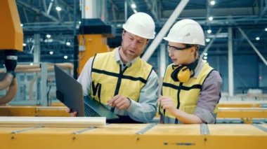 Two specialists are discussing production of a fiberglass frame