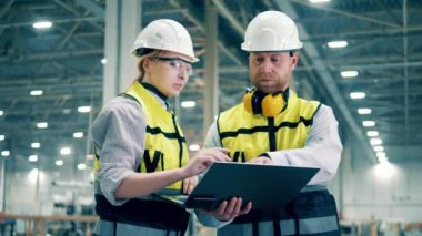 Two specialists are planning constructions in the factory facility