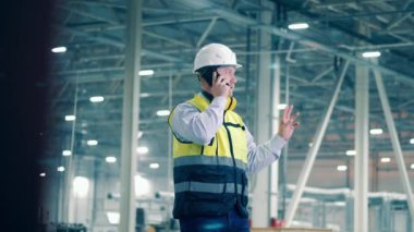 Factory specialist in protection wear is talking on the phone