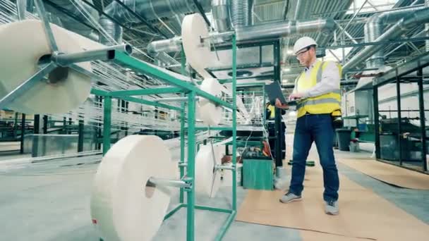 Factory worker is observing fiberglass getting wound into rolls — Vídeos de Stock