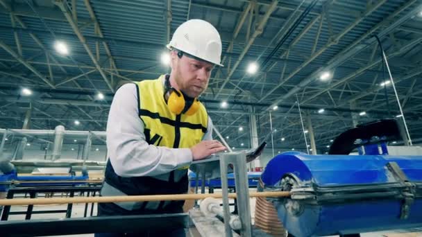 Male specialist with a laptop is examining a fiberglass frame — Vídeo de stock