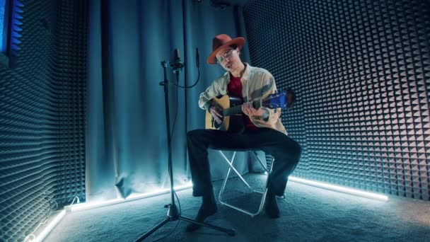 Ein Mann wird aufgenommen, während er singt und Gitarre spielt — Stockvideo