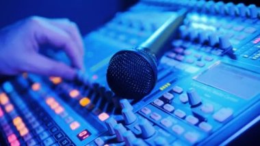 Specialist is operating a mixing consol with a microphone on it. 4K