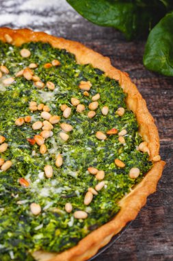 Ispanak, ricotta peyniri ve çam fıstığı ahşap rustik masa üzerinde tart. Yakın çekim