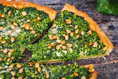 Ispanak, ricotta peyniri ve çam fıstığı ahşap rustik masa üzerinde tart. Yakın çekim