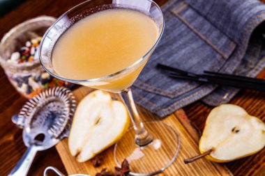 Ahşap masada martini bardağında armut kokteyli. Kapat.