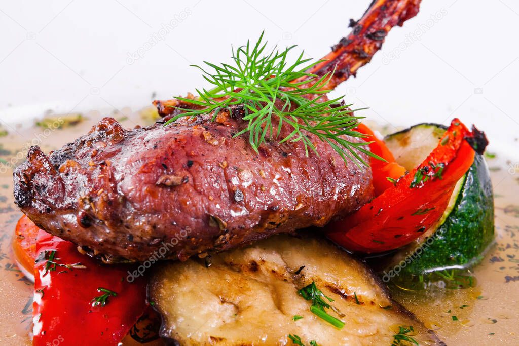 Rack of lamb with grilled vegetables on a white plate