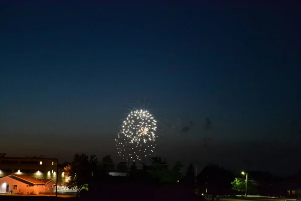 viewing fireworks from a field at night in a small town