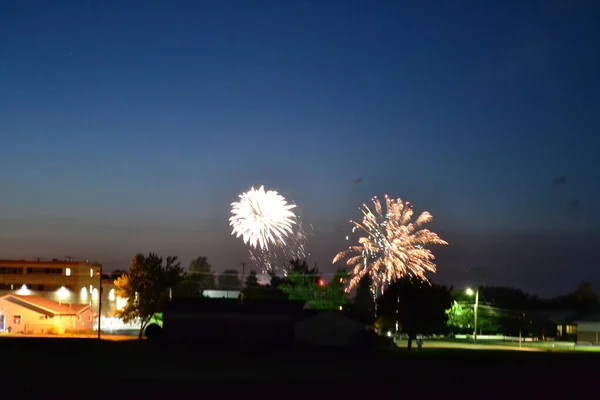 viewing fireworks from a field at night in a small town