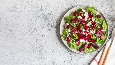 Arugula, pancar ve peynir salatası. Nar ve sos tabakta. Mutfak masasının arka planında.