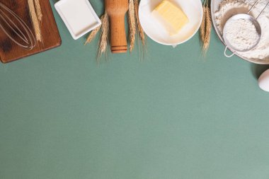 Yeşil pastel arka planda yemek pişirmek için gerekli malzemelerin çerçevesi. Fotokopi alanı olan düz bir yemek pişirme. Üst Manzara. Pişirme konsepti. Model.