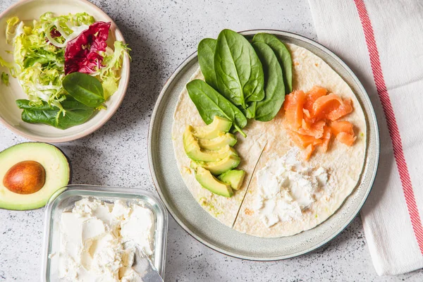 Cooking process for sandwich and ingredients. Process of prepare quesadilla with avocado, salmon, curd cheese and spinach. Trendy wrap hack. Step by step. Step 1