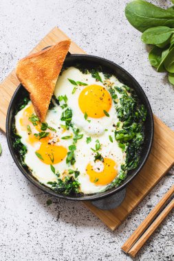 Dökme demir tavada yeşil Shakshuka. Ispanaklı yumurta ve kızarmış tost. sağlıklı besleyici kahvaltı,