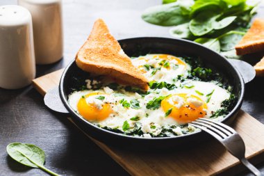 Dökme demir tavada yeşil Shakshuka. Ispanaklı yumurta ve kızarmış tost. sağlıklı besleyici kahvaltı,