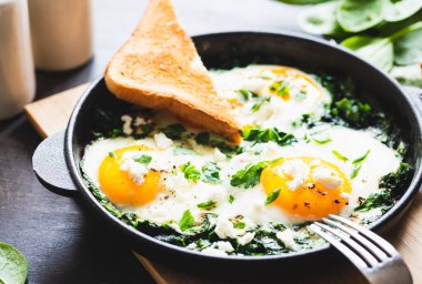 Dökme demir tavada yeşil Shakshuka. Ispanaklı yumurta ve kızarmış tost. sağlıklı besleyici kahvaltı,