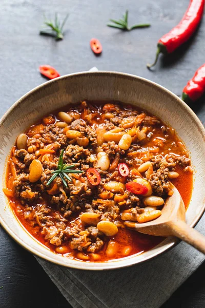 Chili Con Carne in bowl on dark background. Mexican cuisine. chili con carne - minced meat and vegetables stew in tomato sauce. Top view