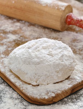 Arkaplanda oklavayla un kaplı hamur pişirme