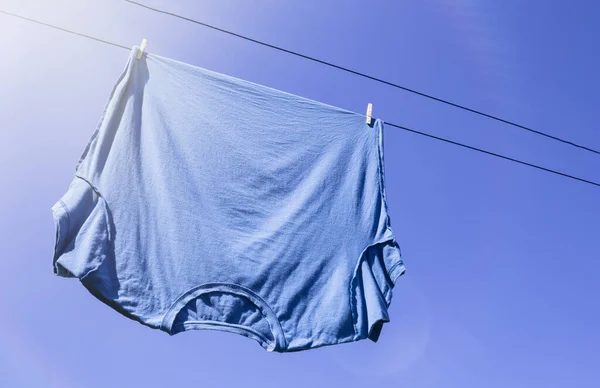 Blue T-shirt on laundry or clothes line with sun flare and copy space