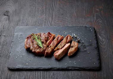 Siyah taş tahtada dilimlenmiş ızgara biftek.