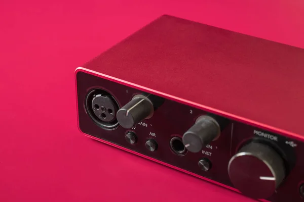 Audio Interface for recording or Home Mixing, red and black external sound card on red background