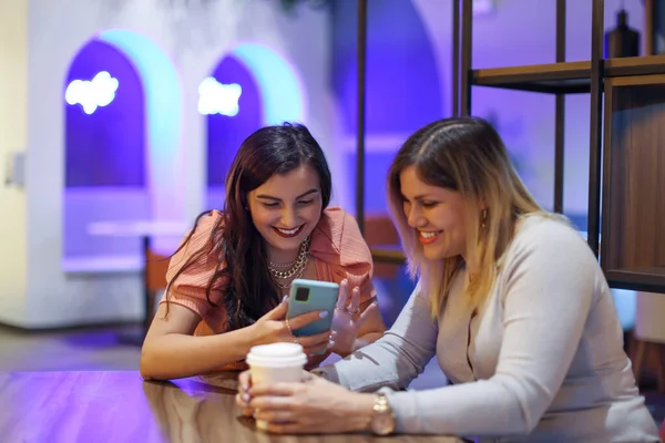 Arkadaşları cep telefonuna bakıyor ve mor arka planlı bir kafede gülümsüyor. Yüksek kalite fotoğraf