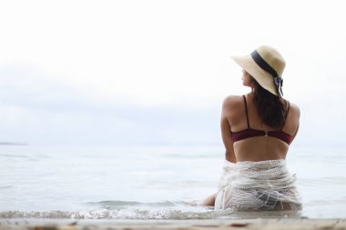 Young woman with bikini and hat looking left sitting at the beach at Bocas del Toro Panama. High quality photo