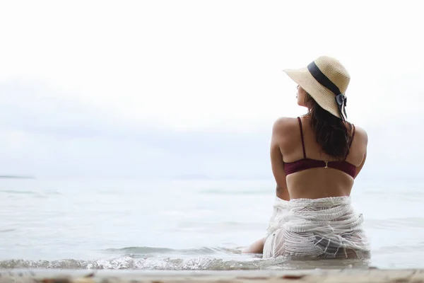 Bikinili ve şapkalı genç bir kadın Bocas del Toro Panama sahilinde oturuyor. Yüksek kalite fotoğraf
