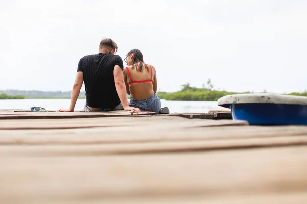 Young couple sitting in dock looking each other at Bocas del Toro Panama. High quality photo