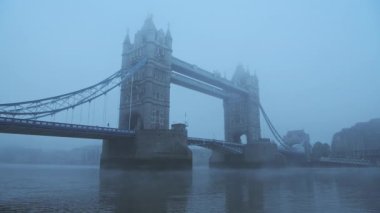 Coronavirus Covid-19 lockdown day one in foggy weather conditions at Tower Bridge in London, with Red London bus driving on a misty cool blue atmospheric morning in fog and mist , England, UK