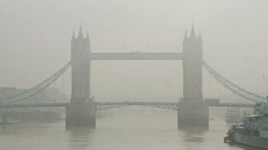 Tower Bridge with red London bus driving over it in foggy misty weather conditions, with mist and fog on the River Thames, shot in the Coronavirus Covid-19 pandemic lockdown in England, Europe