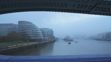 Foggy and misty River Thames in London on Coronavirus Covid-19 lockdown day one, in atmospheric weather with moody blue mist and fog around HMS Belfast and City Hall by Tower Bridge, England, UK