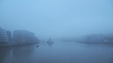 Foggy and misty River Thames in London on Coronavirus Covid-19 lockdown day one, in atmospheric weather with moody blue mist and fog around HMS Belfast and City Hall by Tower Bridge, England, UK