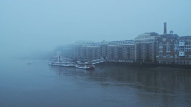 Butlers Wharf Pier and River Thames in thick fog and mist, on a cool blue morning in foggy and misty moody weather in London city centre during Covid-19 Coronavirus lockdown, England, UK