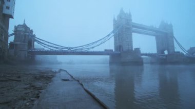 Tower Bridge with red London bus in foggy and misty atmospheric and moody weather conditions on Coronavirus Covid-19 lockdown day one on a blue cool morning, England, UK