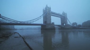 Tower Bridge with red London bus in foggy and misty atmospheric and moody weather conditions on Coronavirus Covid-19 lockdown day one on a blue cool morning, England, UK