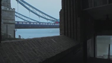 Tower Bridge with red London bus in foggy and misty atmospheric and moody weather conditions on Coronavirus Covid-19 lockdown day one on a blue cool morning, England, UK