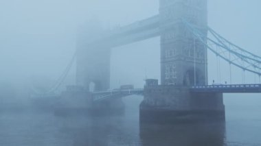 Tower Bridge with red London bus in foggy and misty atmospheric and moody weather conditions on Coronavirus Covid-19 lockdown day one on a blue cool morning, England, UK