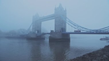 Tower Bridge with red London bus in foggy and misty atmospheric and moody weather conditions on Coronavirus Covid-19 lockdown day one on a blue cool morning, England, UK
