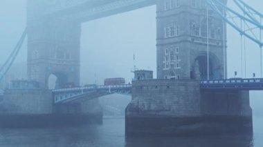Red London bus driving on Tower Bridge on a misty cool blue atmospheric morning in fog and mist on Coronavirus Covid-19 lockdown day one in foggy weather conditions, England, UK