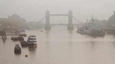 Tower Bridge with red London bus driving over it in foggy misty weather conditions, with mist and fog on the River Thames, shot in the Coronavirus Covid-19 pandemic lockdown in England, Europe