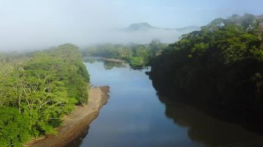 Aerial Drone View of San Carlos River (Rio San Carlos) in Costa Rica, that Connects to Nicaragua, with Lush Green Misty Rainforest Scenery and Misty Mountains, Central America