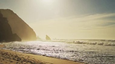 Praia Da Adraga Beach in Portugal, Lisbon (Lisboa) at Beautiful Orange Sunrise, With Waves Breaking on Sandy Shore and Rock Formations on Dramatic Portugese Coast Landscape at Sintra, Europe