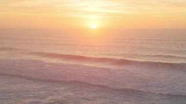 Beautiful Waves Breaking Ocean Seascape Background at Sunset with Sun Setting, Pastel Muted Warm Orange Colours from Elevated Aerial Drone View