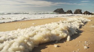 Sea Foam (aka Beach Foam, Ocean Foam or Spume) on a Sandy Beach on the Atlantic Coast of Portugal at Sintra, Lisbon, Europe