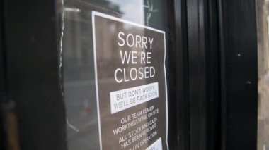 Coronavirus Covid-19 information sign in a shut shop window saying sorry we are closed during London lockdown on an empty shopping high street in England, Europe