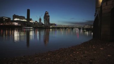 Tate Modern and London city skyline with lights lit up at night on the River Thames beach at low tide by Millennium Bridge, shot in Coronavirus Covid-19 pandemic lockdown